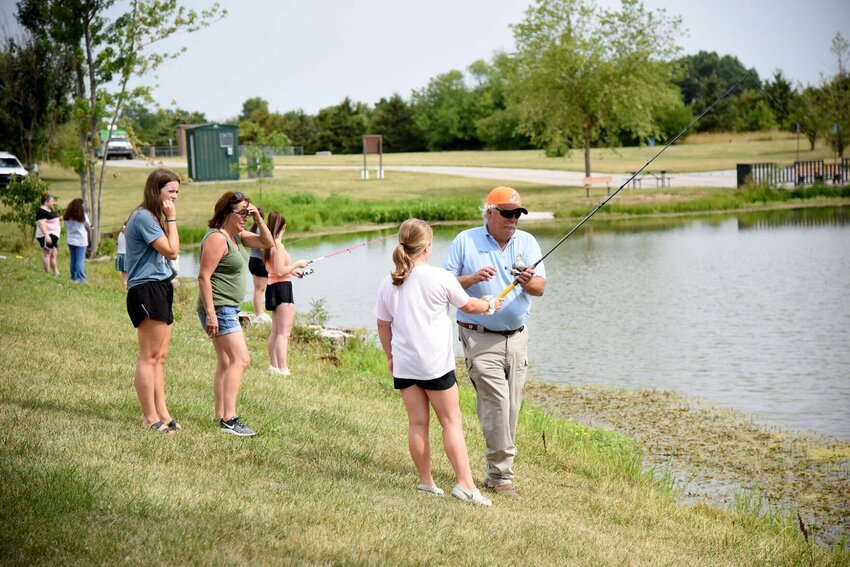 Missouri Department of Conservation Educator Mark Miller helps a Skyline Elementary student with her fishing pole Thursday morning, July 6 at Clover Dell Lake. The first-time event, &ldquo;Fishing with the Counselor and Social Worker,&rdquo; was organized by Sarah Moore, Skyline&rsquo;s special services social worker, and Meagan Klein, the school&rsquo;s counselor.   Photo by Faith Bemiss | Democrat