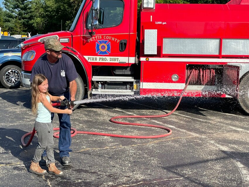 A Boys &amp;amp; Girls Club member gets a little help from a Pettis County Fire Department firefighter to spray the burn house at the 2022 National Night Out event. This year&rsquo;s event is slated for Aug. 1.   Photo courtesy of Boys &amp;amp; Girls Clubs of West Central Missouri