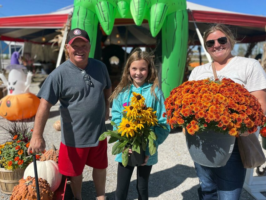 Tory Meade with Hale's Fall Harvest on West U.S. Highway 50 hauls a wagon of pumpkins Monday, Oct. 9 as Ava and Taylor Pfeiffer, of Holden, purchase fall decorations for their Holden home.   Photo by Chris Howell | Democrat