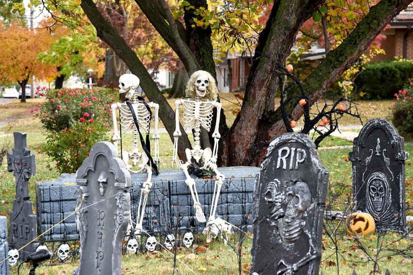 Two skeletal lovers sit under an autumn tree along the 1600 block of West 16th Street. The Halloween decorations include a vintage hearse drawn by a horse skeleton, gravestones, jack-o-lanterns, and giant spiders.   Photo by Faith Bemiss-McKinney | Democrat