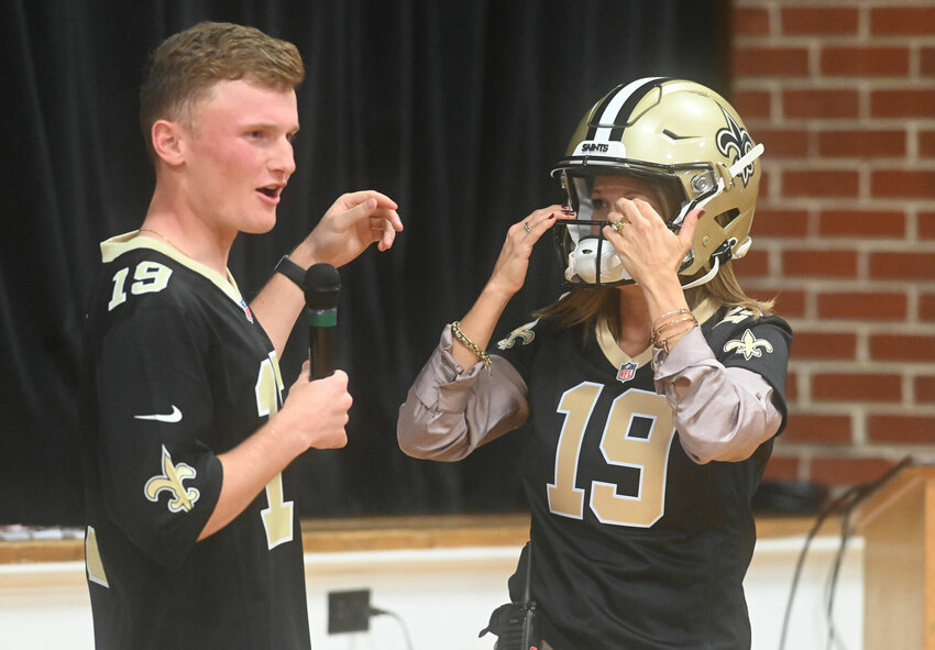 New Orleans Saints kicker and Sedalia native Blake Grupe, left, fits Horace Mann Elementary principal Sara Pannier into some gear during Thursday afternoon's visit to talk to students as part of his trip home on the Saints' bye week.   PhotoCredit: Photo by Bryan Everson | Democrat