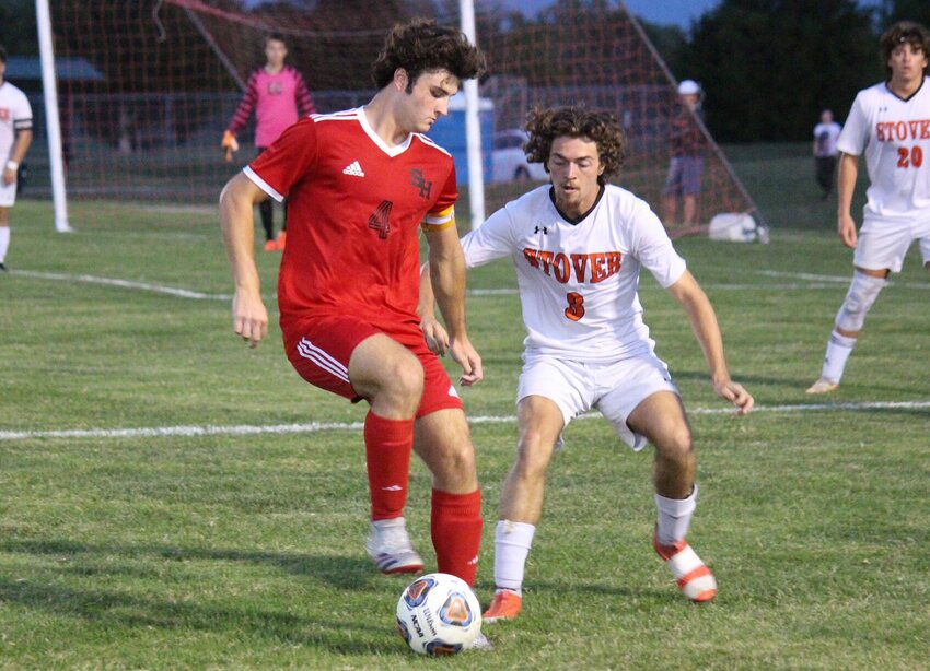 Sacred Heart senior George Bain works to keep possession from Stover's Kolten Carter (3) in the attacking half during Tuesday's match at Clover Dell Park in Sedalia.   PhotoCredit: Photo by Bryan Everson | Democrat