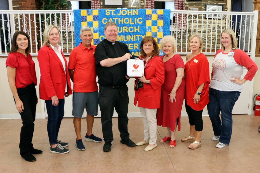 St. John&rsquo;s Community Center received an automatic external defibrillator. From left, Rhonda Ahern, committee member; Dianne Simon, Thompson Hills Investment Corporation vice president and committee co-chair; Tom Dey, St. John the Evangelist parishioner; Fr. Joe Corel, St. John the Evangelist pastor; Lori Wightman, Bothwell CEO and committee co-chair; Connie McLaughlin and Trish Henson, committee members; and Lauren Thiel-Payne, Bothwell Foundation executive director.   Photo courtesy of Bothwell Regional Health Center