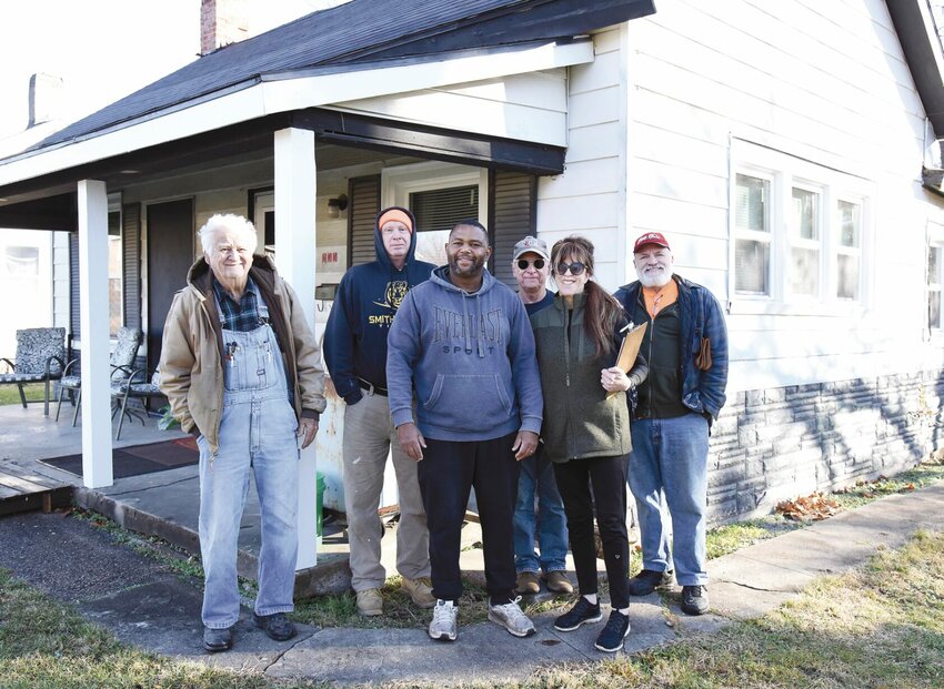 On Saturday, Dec. 9, Helping Hands nonprofit group members, from left, Wayne Rhoads, Tom Beatty, Board President Traves Williams, Steven Hession, Sharyn Fante-Hession, and Jethro Christopherson stand by a home on North Moniteau Avenue that they have helped to get up to city code.   Photo by Faith Bemiss-McKinney | Democrat
