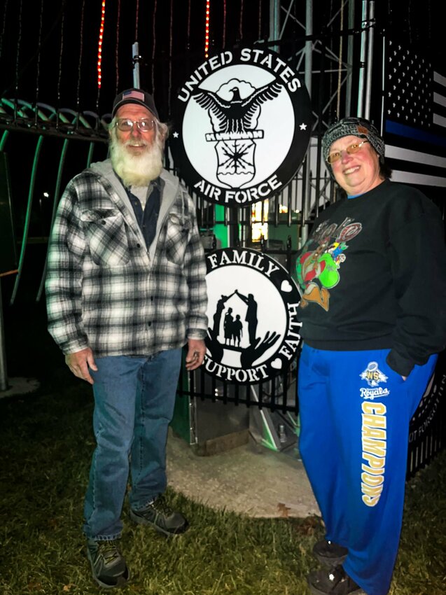 Donna and David Grygierczyk pose under the 41-foot-tall Tribute Tree at the Country Christmas Acres in Knob Noster. After 41 years, the couple has decided that 2023 will be the last Christmas season for their annual holiday light show and display.&nbsp;   Photo by Annelia Nixon | Warrensburg Star-Journal