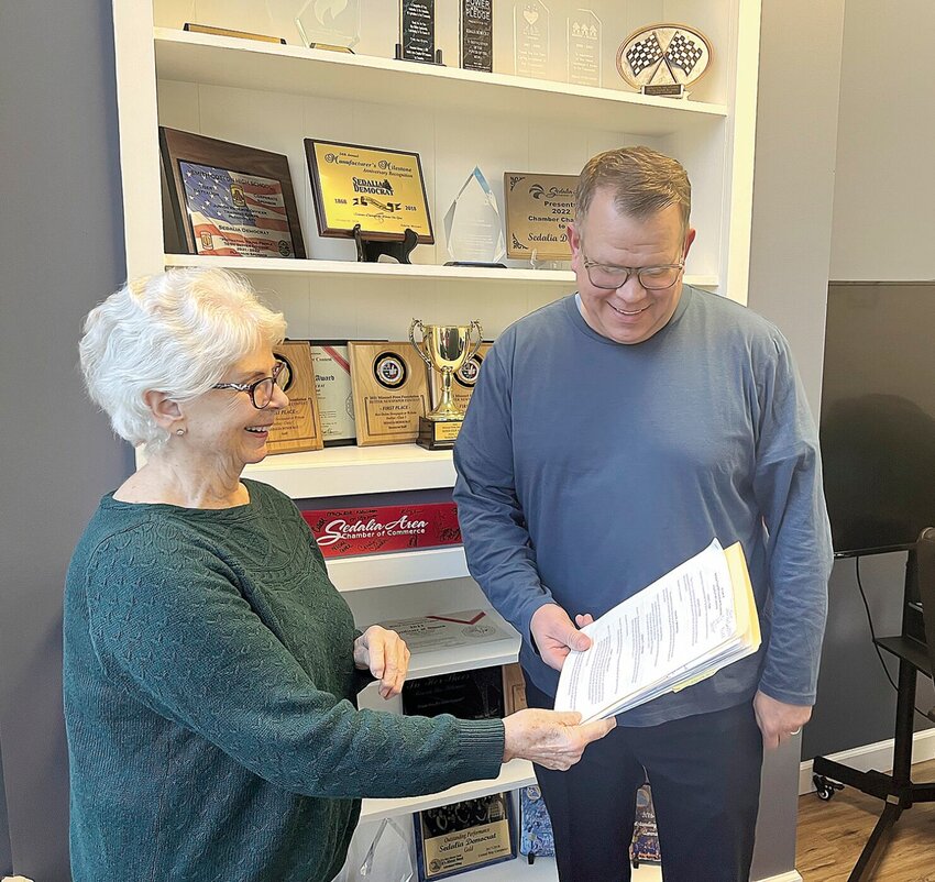 On Thursday, Dec. 28, Linda Hoover, 77, the former president of the Sedalia Visual Art Association, passes a folder of information to new SVAA President Dustin Schmidt. Hoover, who was president for eight years, is stepping down due to health concerns.   Photo by Faith Bemiss-McKinney | Democrat
