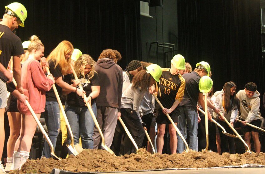 Members of various Smith-Cotton sports grab shovels and turn over dirt during the groundbreaking ceremony for the Jennie Jaynes Activities Complex expansion in the Heckart Performing Arts Center Monday night.   Photo by Jack Denebeim | Democrat