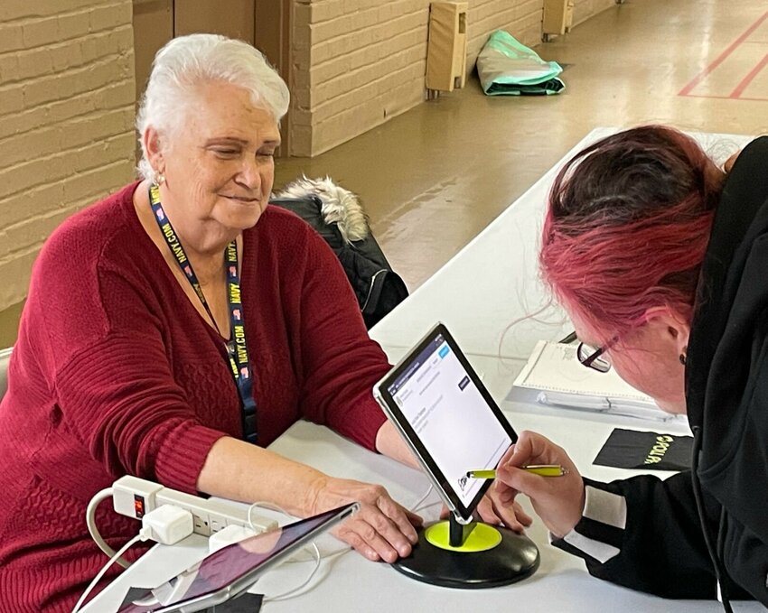 Poll worker Linda Casey helps voter Josey Trautman sign in to cast her ballot Tuesday, April 2 at Convention Hall. Poll workers noted a light turnout for the municipal election.   Photo by Chris Howell | Democrat