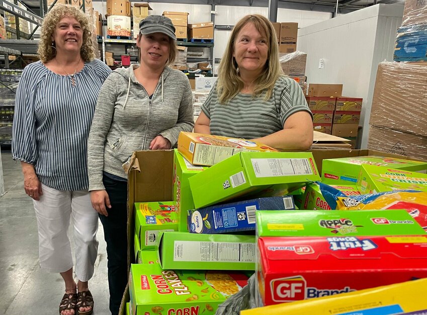 On Thursday, April 18, from left, Open Door Development Director Michelle O'Donnell, warehouse lead&nbsp;Allison McIntyre and supervisor Victoria Powell stand in the food pantry warehouse by a huge box of cereal recently donated by First Christian Church of Sedalia and local Menards employees.   Photo by Chris Howell | Democrat
