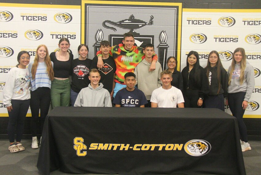 Smith-Cotton senior Jorge Contreras, sitting, center, celebrates signing his letter of intent to join the State Fair Community College cross country team with members of the Smith-Cotton cross country team Friday.   Photo by Jack Denebeim | Democrat