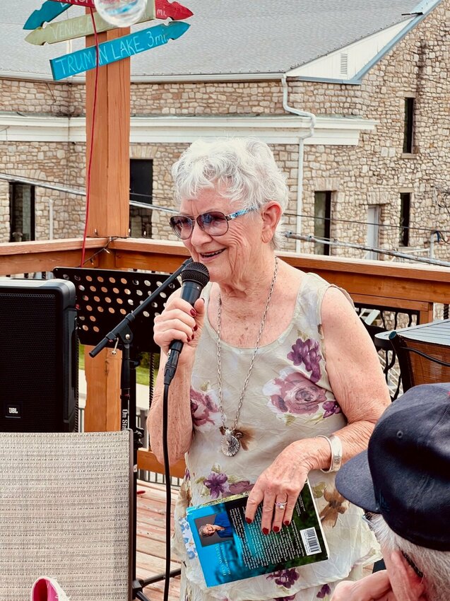 Author Lela Merrell Savage prepares to read from her fiction book, &quot;River James and Saturday,&quot; on Saturday, June 1 at the Benton County ArtFest's second annual Open Mic event in Warsaw. Savage, of Warsaw, has written about her childhood in Benton County many times, and included elements of it in her novel, which is a murder mystery and romance book. Emcee for the event was retired educator and author Debbie Noland.   Photo by Faith Bemiss-McKinney | Democrat