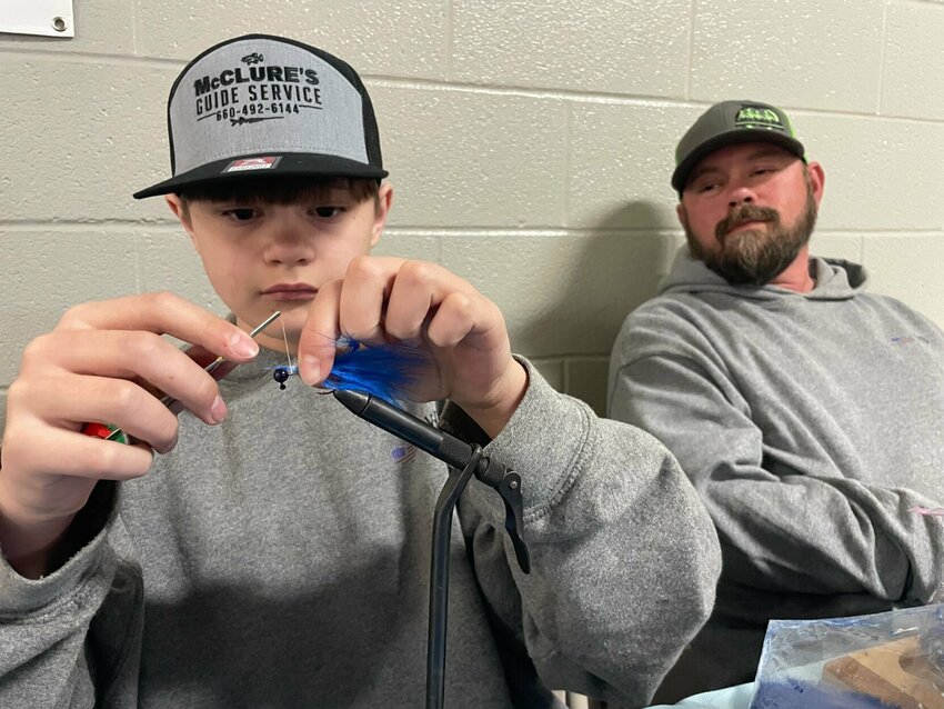 !2-year-old Drake Davis ties custom jigs at the Mathewson Exhibition Center Friday at the Central Missouri Ag Expo. Matt Davis is impressed with his son's focus on creating a better fishing lure.


Photo by Chris Howell | Democrat