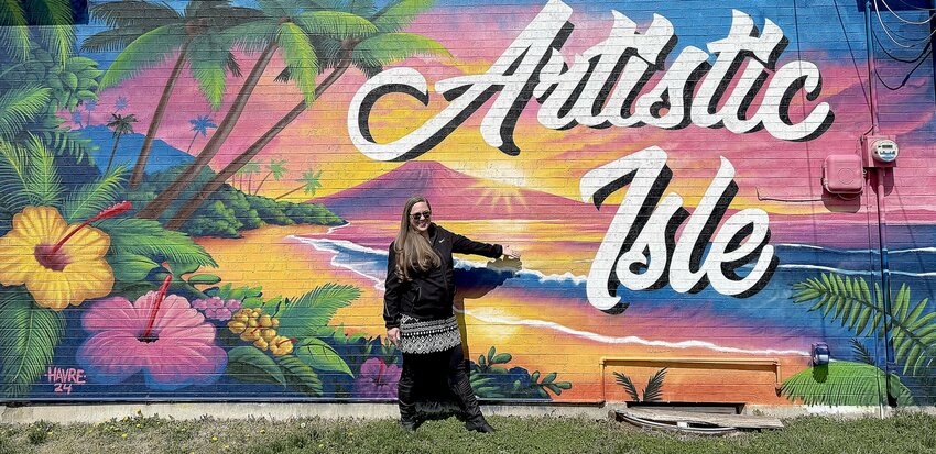 On Wednesday, March 26, Lindsey Starr, owner of Artistic Isle in downtown Sedalia, stands outside her building next to a mural created by Paul Woronecki of Lincoln. She opened the art supply business in 2023 and offers art classes.   Photo by Faith Bemiss-McKinney | Democrat