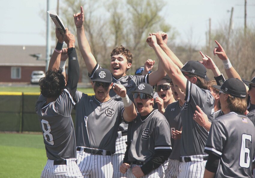 Smith-Cotton senior Jakobe Linn (8) hoists the Smith-Cotton Tournament championship trophy as the rest of the team celebrates on Saturday, April 12, at Smith-Cotton High School. The Tigers beat Lone Jack 5-1 to win the title.   Photo by Jack Denebeim | Democrat