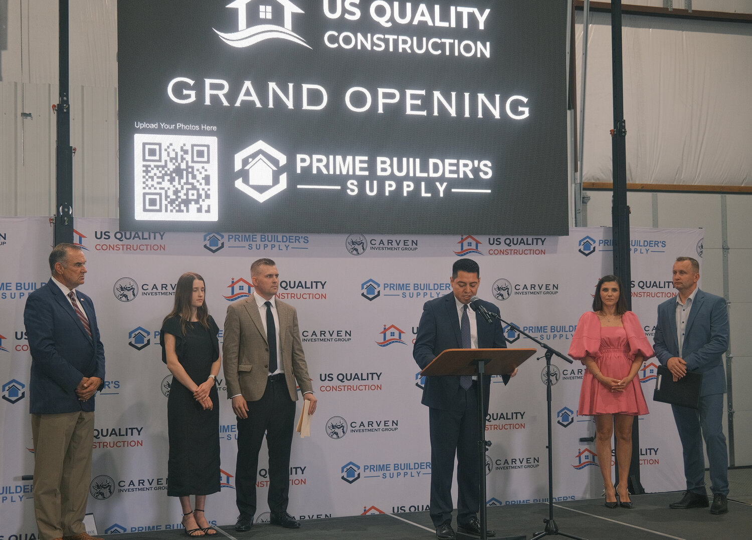 Gov. Mike Kehoe, Maryka Kondratyuk, Tim Kondratyuk, Pettis County Eastern Commissioner Israel Baeza, Vera Tutevich and Vladimir Tutevich standing on the podium Tuesday, June 3, at the US Quality Construction, Prime Builder’s Supply Grand Opening.