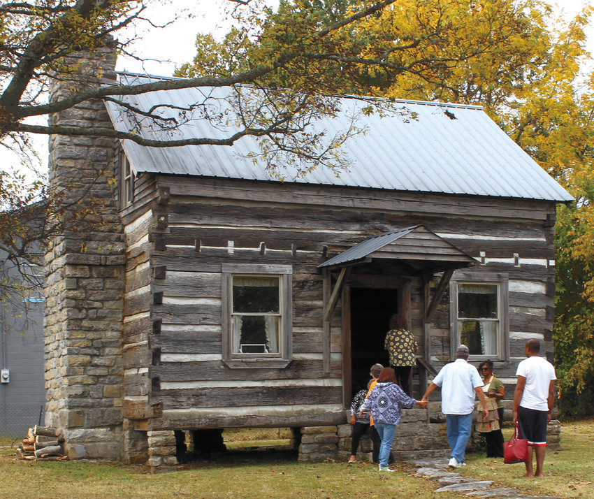 Visitors enter the log cabin behind the Gilliland House.