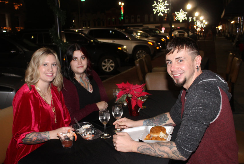 From left, Casie Stewart, Kayla Harris and J.J. Stewart enjoy snacks under the square&rsquo;s Christmas lights.