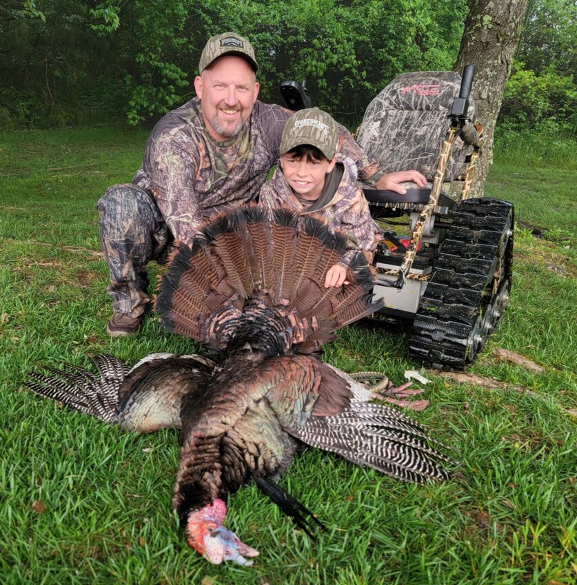 Chad Boyce with one of the children, who sits in an all-terrain wheelchair, proudly displaying their turkey.