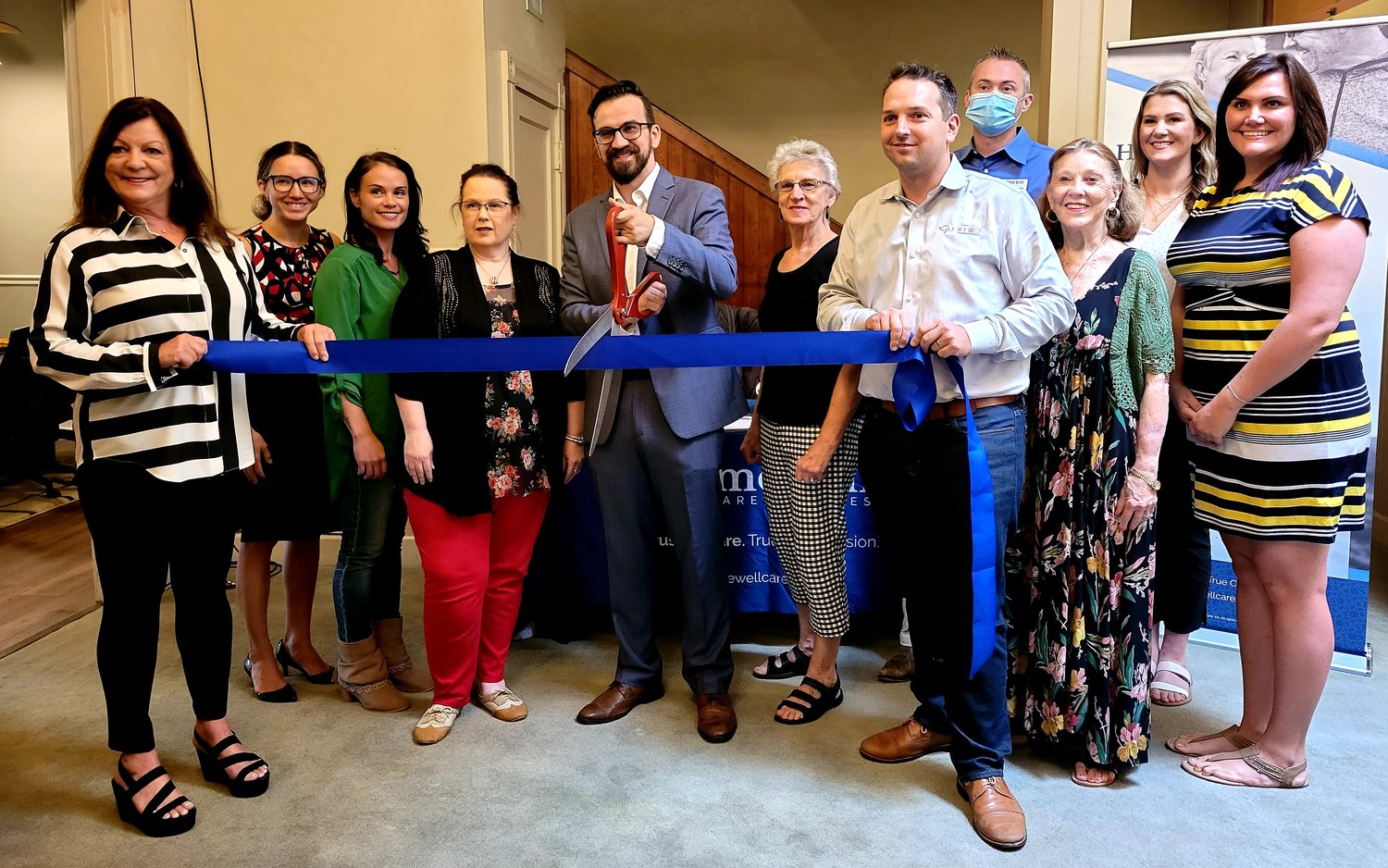 Boris Zecevic, center, opened HomeWell Care Services in March. A ribbon cutting was held on Aug. 19 to commemorate their new office location on the public square.