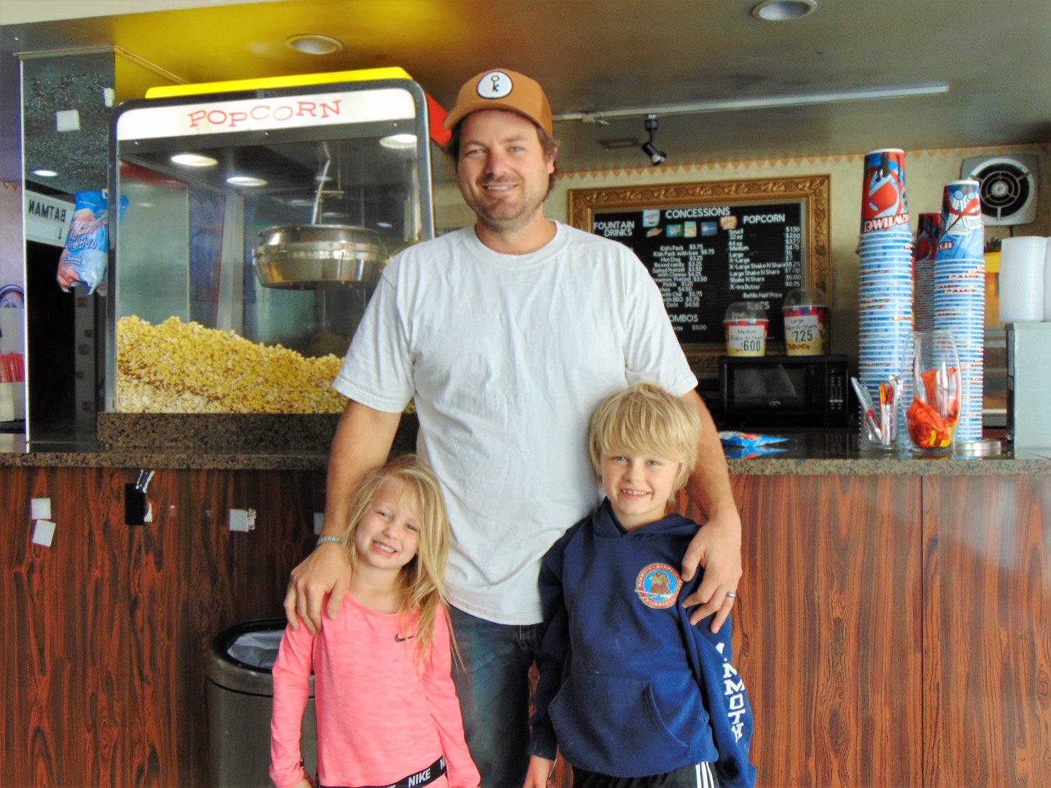 Patrick Curtis stands in front of nostalgic, theatre concession stand with his daughter Eisla, left, and son Emmett.