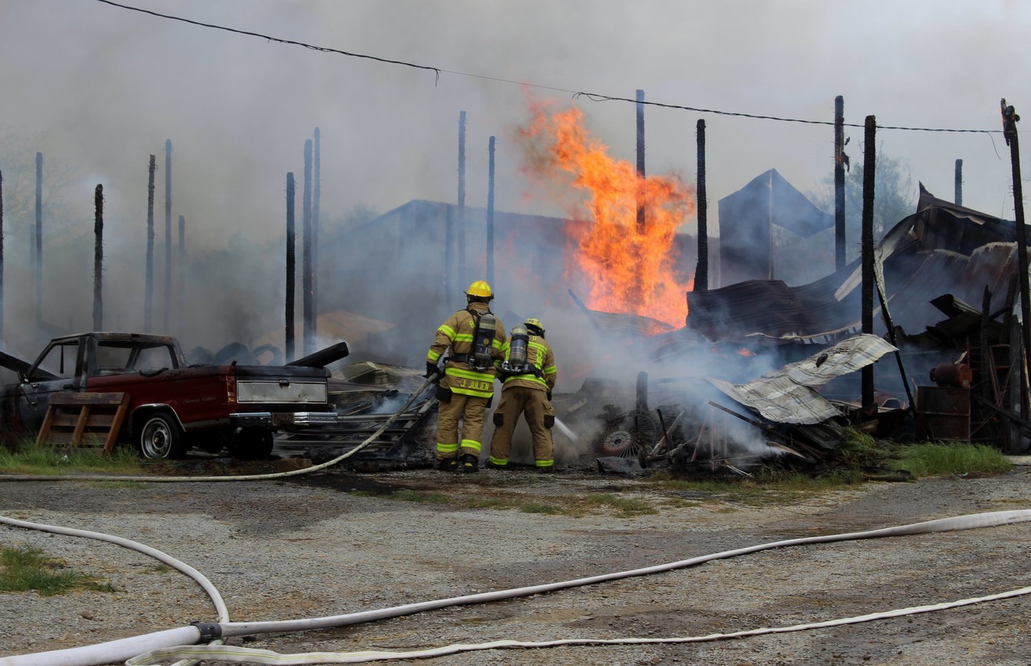 Bedford County firefighters spray flames in barns at the  M & L Greenhouse complex Friday afternoon.