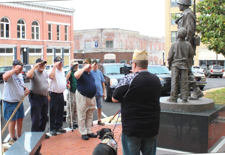 Soldiers salute before getting to their duties of cleaning up Veterans Plaza on the square. Army veteran Dave Rogers videos the occasion.