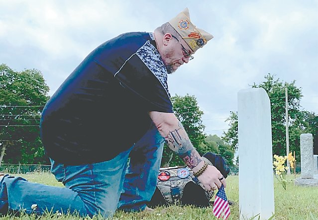 U.S. Army veteran Dave Rogers and service dog, “Grunt,” place an American flag
on the gravesite of SPC Larry Buchanan at Willow Mount Cemetery.