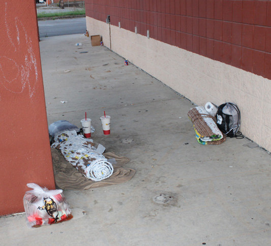 Bedrolls and discarded fast-food wrappers litter an area near the front of the empty store where an individual often sleeps at night.