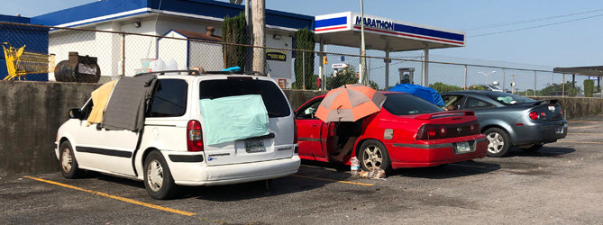 Several people live in their vehicles behind the Marathon convenience store at Lane Parkway and North Cannon Boulevard. The sign on the van reads, “Homeless Can You Help Us Please? We Need Gas + Food.”