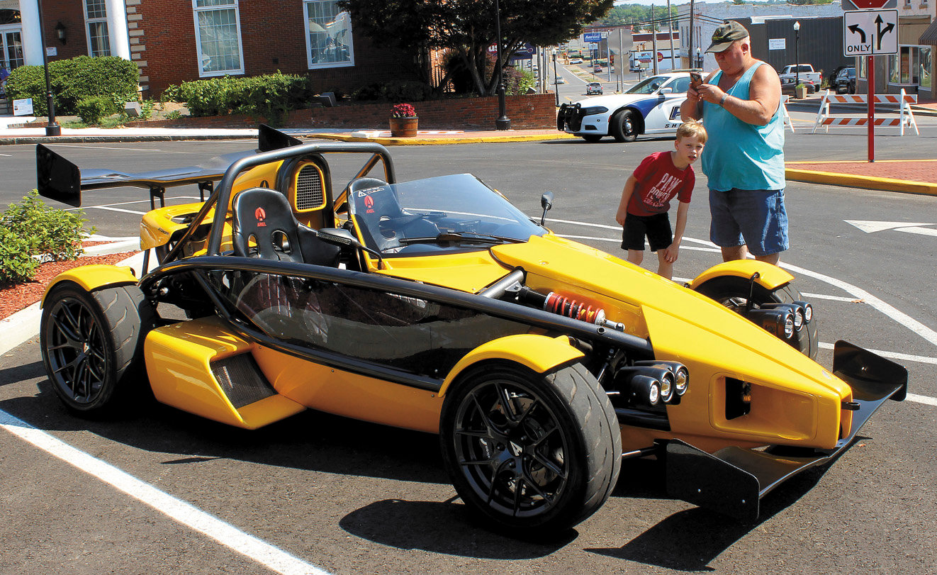 Doug Wisdom and his grandson, Lestat Wisdom, are looking at a rarely-seen Ariel Atom sports car.