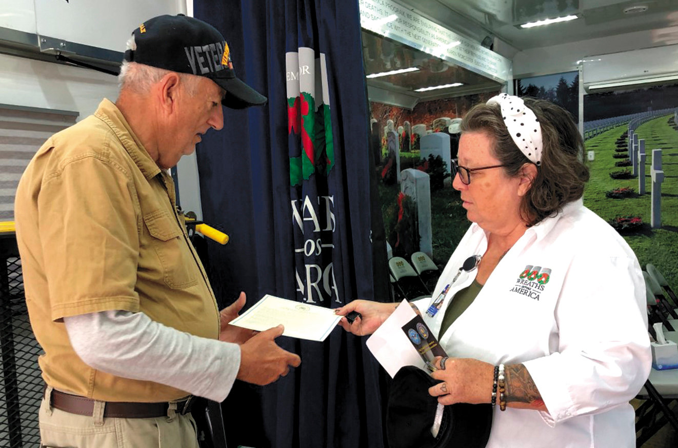Leverette receives a cap and several other items from Deborah Kellogg, a Wreaths Across America driver/ambassador from Maine. Long-haul truck drivers volunteer their time to drive the large exhibit trailer around the nation.