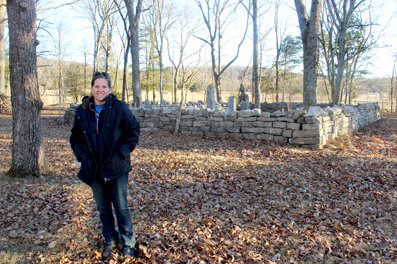 Brooke Smith-Sanders stands near the fenced Coop burial grounds within Church Cross Cemetery. Smith-Sanders, whose father is buried in the cemetery, is working toward cleaning the property.