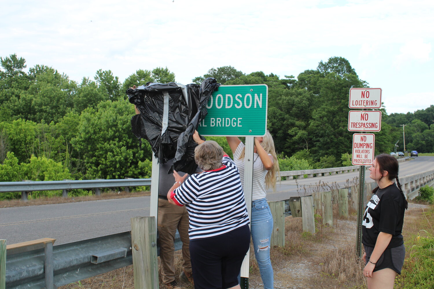 Members of the Woodson family unveil the sign identifying the bridge.