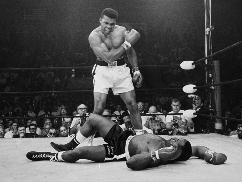 Muhammad Ali towering over a floored Sonny Liston at their second encounter for the heavyweight title (May/1965). Speculation remains that Liston took a dive on a &quot;phantom punch&quot;.