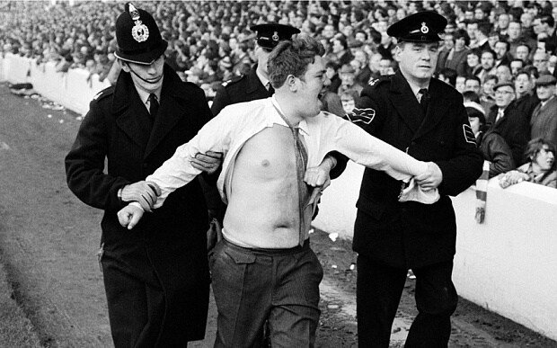A rowdy fan being escorted by police at an English football match (circa early 1970s). Soccer hooliganism was a scourge on British society during the 1970s and 1980s.