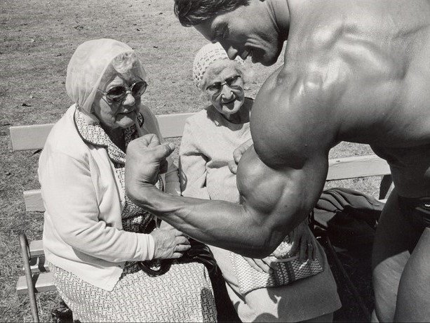 Arnold Schwarzenegger displaying his goods in front of two older ladies. The 1977 film "Pumping Iron" made him a household name and helped push bodybuilding into mainstream America.
