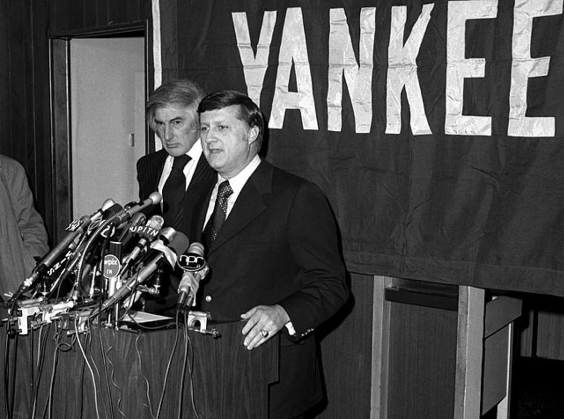 George Steinbrenner and Michael Burke (standing behind) announcing their purchase of the New York Yankees for $10 million on January 4th, 1973. The following year, Burke would be out the door as senior executive of the team and Steinbrenner would begin his imperious ownership of the club, turning the Yankees brand into today's $5 billion sports property.