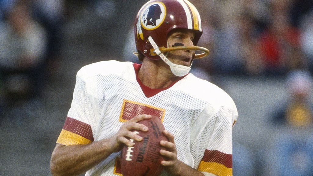 Joe Theismann in action with the Washington Redskins. One of the best quarterbacks of the 1980s, Theismann led his team to victory at Super Bowl XVII and the NFC championship the following year. A severe leg injury in 1985 put an end to his playing days, but the undeterred athlete and lover of the game went on to a successful career in broadcasting.
