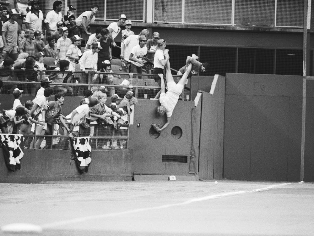 A fan is lowered upside down by his friends to retrieve a ball. Until "Reuben's Rule" was born, spectators risked being arrested for keeping a foul ball.