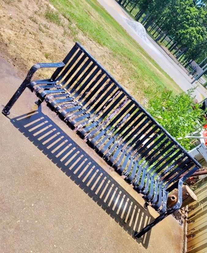 Pictured is the bench Truitt painted as it is being restored to its original state in a different location. The bench could not be restored on the sidewalk in its original location because the paint could have damaged the concrete sidewalk below it. The restoration process was too complicated to do on site.