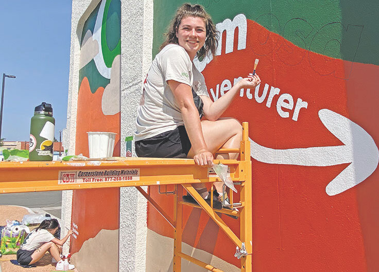 On scaffold, Cat Flaherty-Ng (lower left) and Shaye Vanderbille are working on the Alamosa Adventurer mural in downtown Alamosa on July 25.