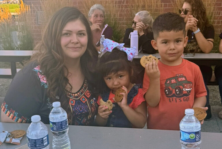 Jazmine Pena sitting at a table enjoying Center Consolidated School District’s community open house with her kids on Aug. 15.