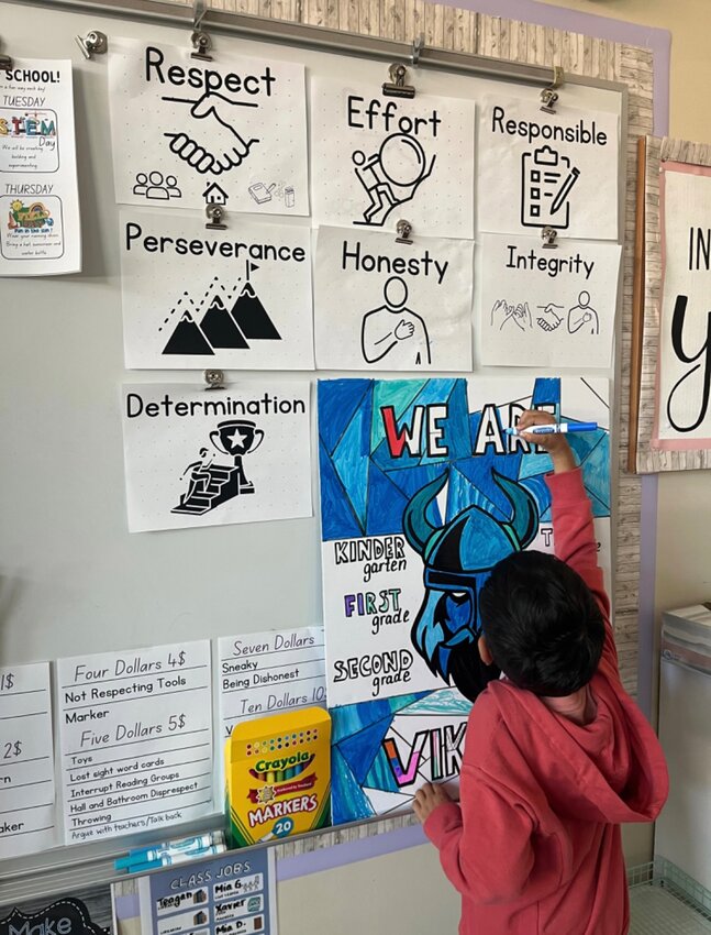 A first-grader at Center Elementary colors a portion of a poster as part of the Super Student program. 