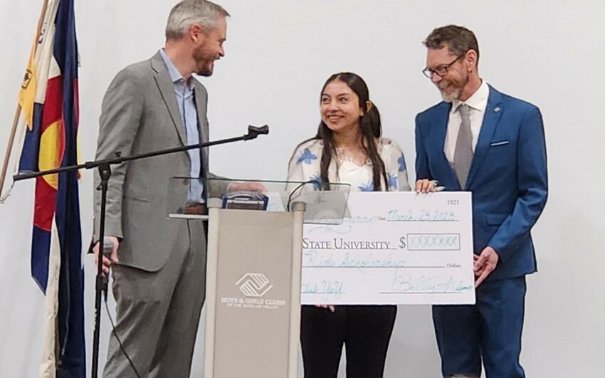 Adams State University President David Tandberg (left) presents Myissa Duran (center), BGCSLV 2025 Youth of the Year with a scholarship after being brought to the stage by Boys and Girls Clubs of the San Luis Valley President Aaron Miltenberger.  The event was held Tuesday morning. 