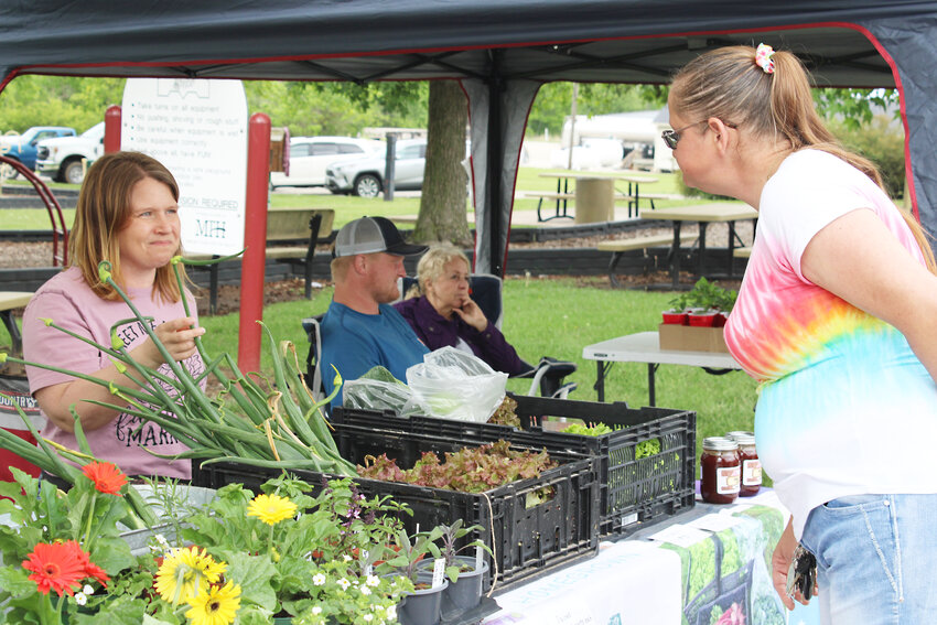 Opening day - Gabe Branstetter visits with customer Virginia Albrecht on opening day of the Eldon Farmers Market Friday afternoon, May 3 at Rock Island Park. Good weather and a variety of products greeted market-goers. The market is open from 3 to 6 p.m. each Friday through September with homegrown produce and local, hand-crafted items.
