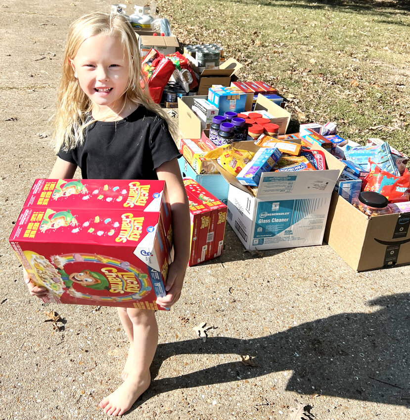 Cereal and a smile – Ada Kempker carries a large box of cereal to  put in the food organizing area.