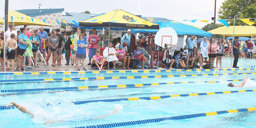 Splashes and showers – Swimmers, parents and friends watch the Mid-Missouri Championship meet Saturday, July 13. Swimmers contended with rain and a lightning delay during the first part of the meet with the rain ending about 1 p.m.