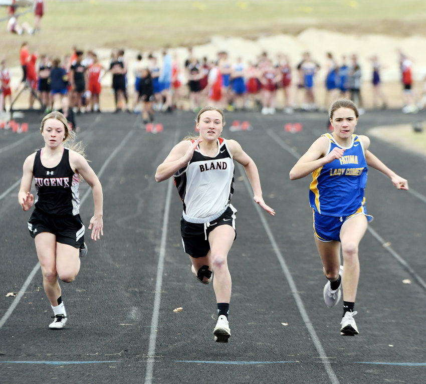 Aubrey Rehmert (center) sprints down the track in the 100-meter dash for Bland&rsquo;s Lady Bears during their season-opening track meet Monday afternoon at the Osage County Fairgrounds in Linn.