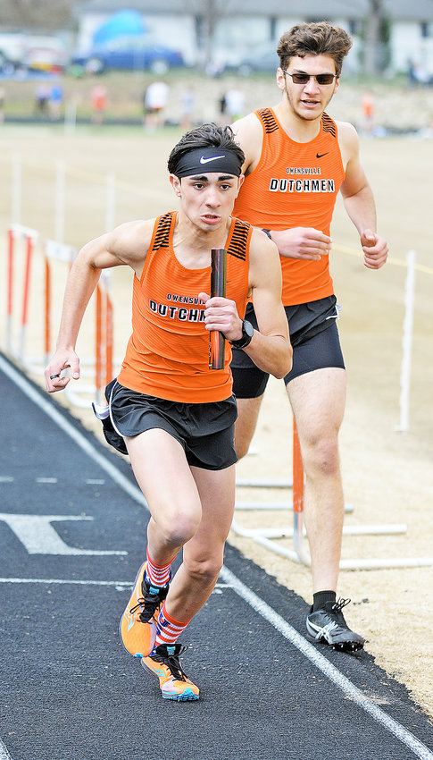 Lucas Morgan (left) secures the baton from Felix Guerrero for the Owensville Dutchmen 4x800-meter relay team south along Highway 19 in Crawford County last Tuesday night.