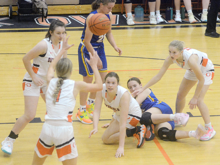 Kiana Guerrero (center) watches the ball sail into the waiting hands of Emma Daniels after she stole late in Owensville&rsquo;s 63-32 season-opening girls basketball victory Monday night over the visiting St. Francis Borgia Lady Knights at Owensville High School.